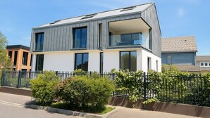 Ein modernes, zweistöckiges Haus mit großen Fenstern und einem Balkon.
