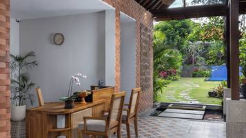 Un comedor con una mesa y sillas de madera, una planta en maceta y un reloj en la pared.