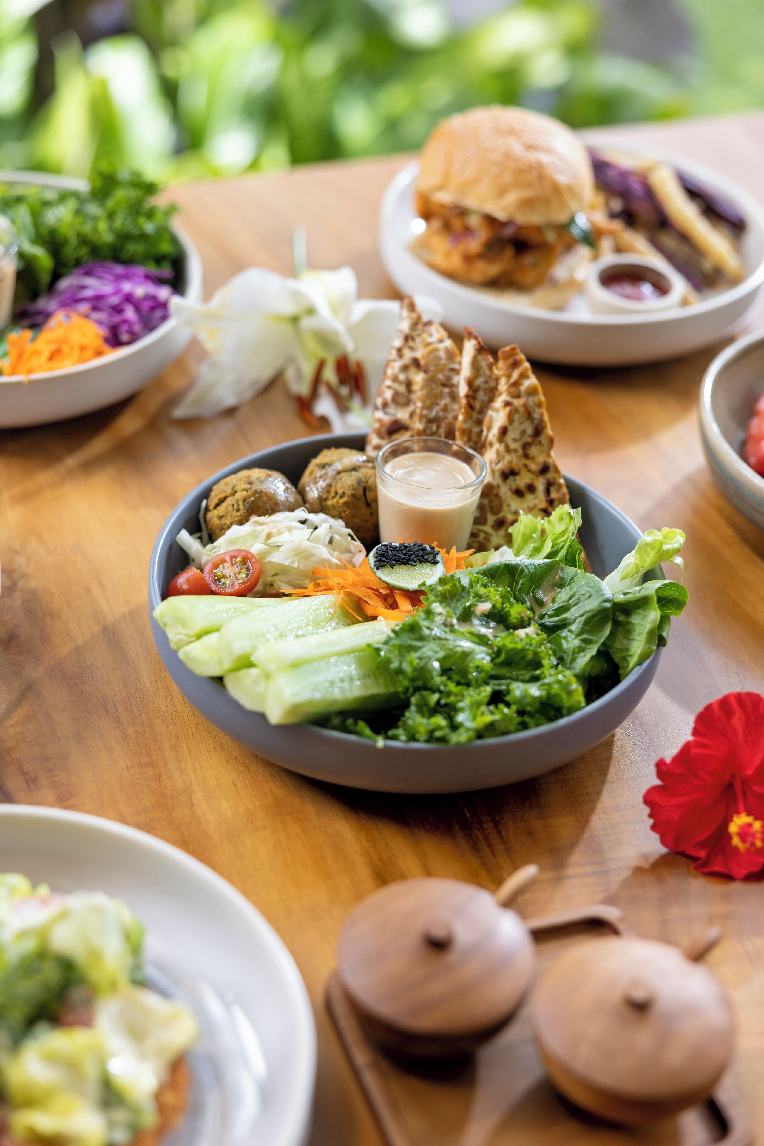 A dining table with various dishes including a salad, burger, and fries.