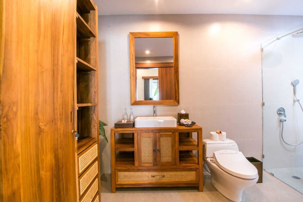 A bathroom with a wooden vanity, a mirror, a toilet, and a shower.