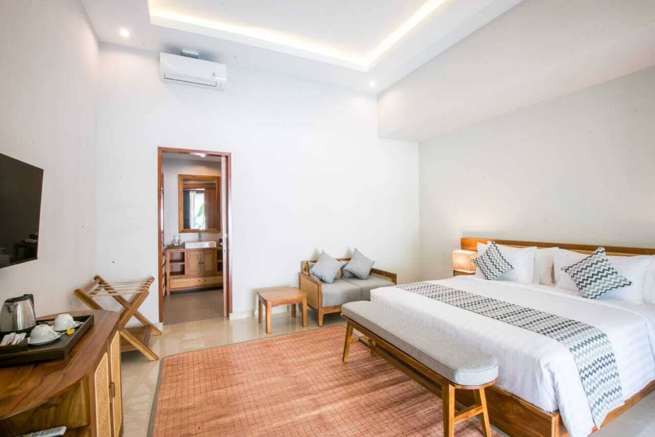 Ein Hotelzimmer mit Bett, Nachttisch, Stuhl und kleinem Schreibtisch mit einer Anrichte.