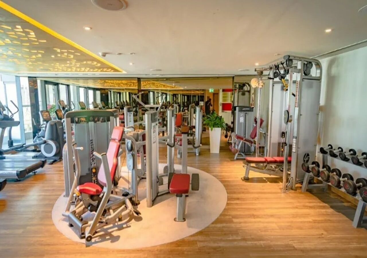 Ein Fitnessstudio mit verschiedenen Trainingsgeräten, Laufbändern und Kurzhanteln.