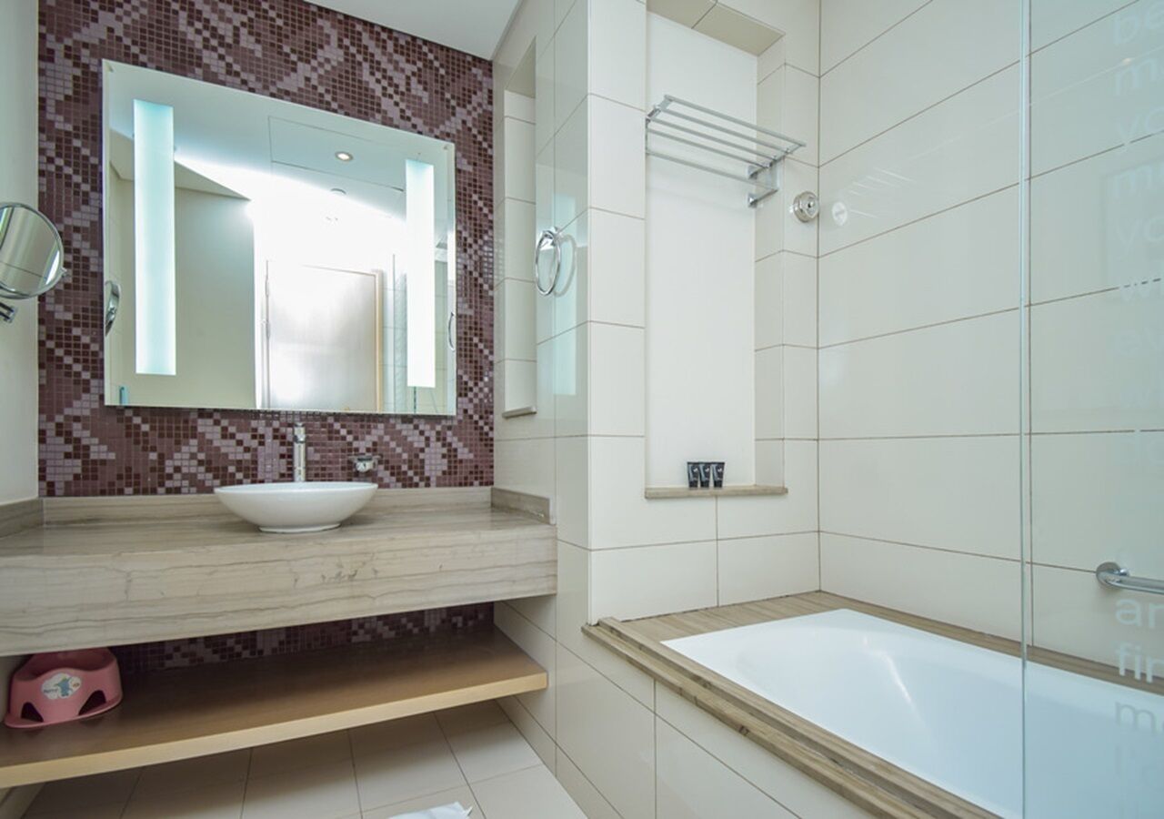 A modern bathroom with a large bathtub, a white sink, and a mirror above the sink.