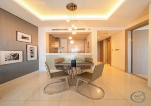 A modern dining area with a round table and chairs, a ceiling light fixture, and framed pictures on the wall.