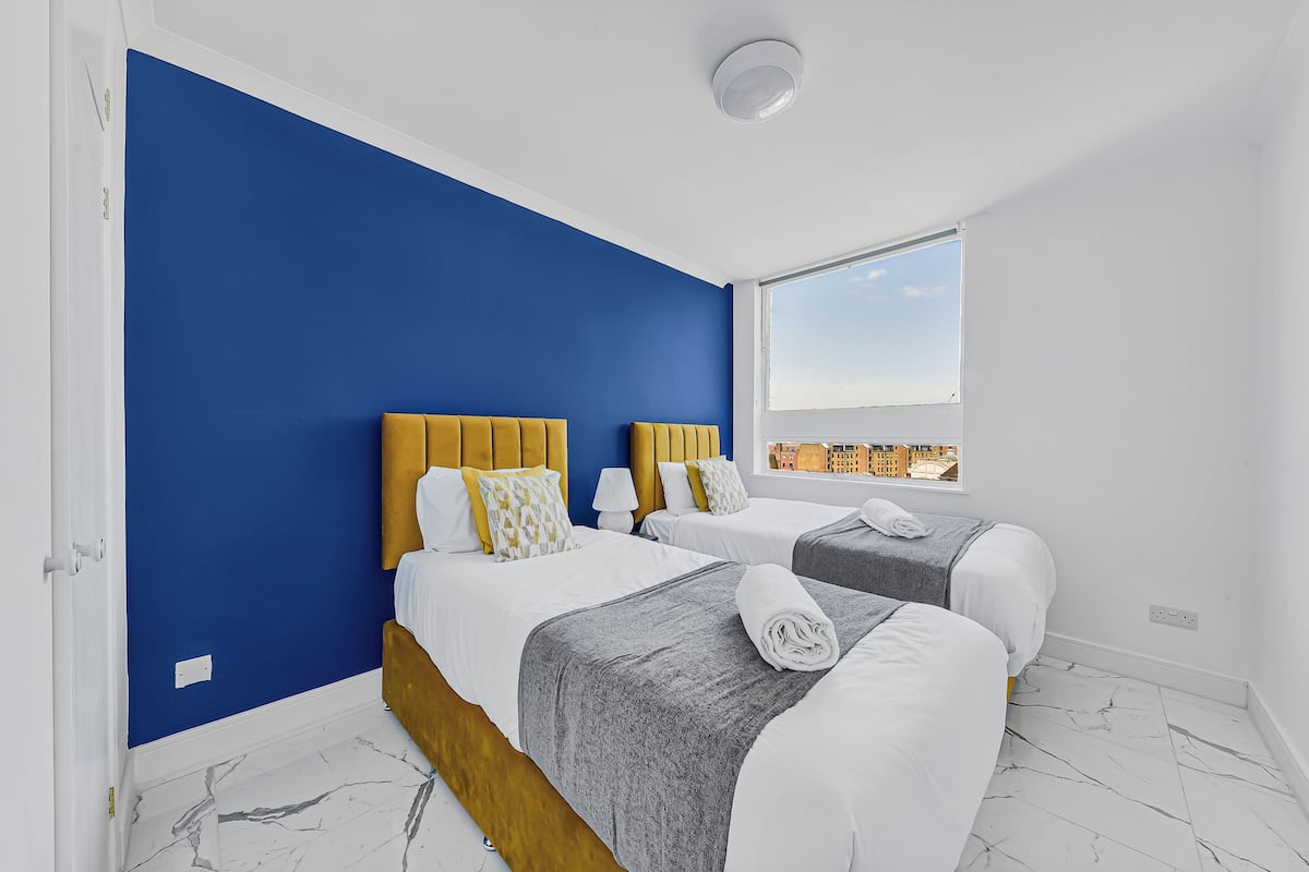 A hotel room with two beds, a large window, and a city view.