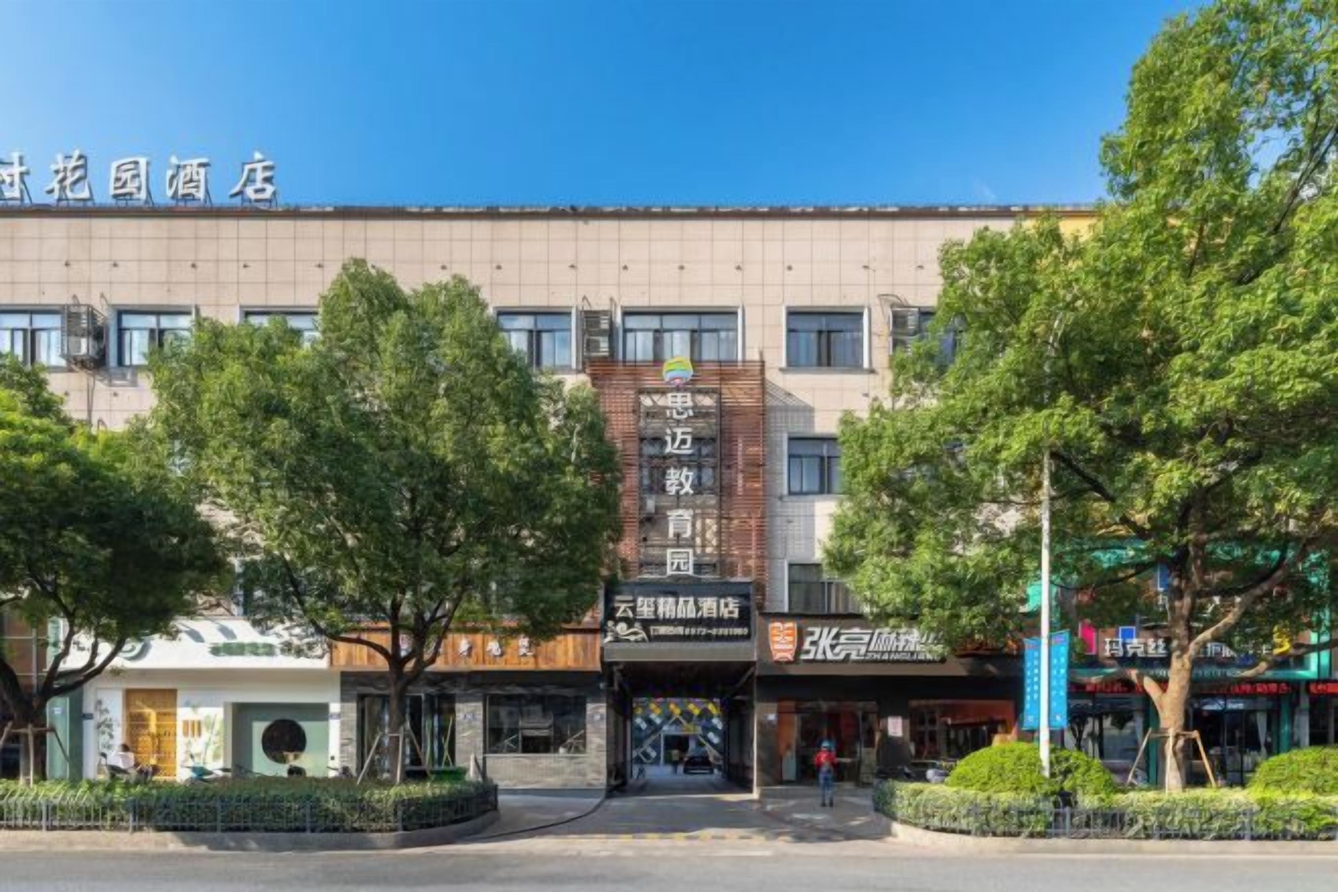 A hotel with a modern facade, a central entrance, and a landscaped courtyard.