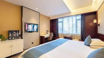 Una habitación de hotel con una cama grande, un escritorio, un televisor y un armario.