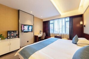 Ein Hotelzimmer mit einem großen Bett, einem Schreibtisch, einem Fernseher und einem Schrank.