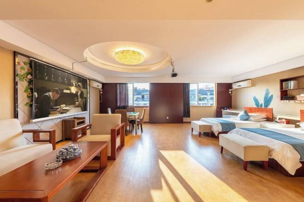 Habitación de hotel con televisión, sofá, mesa de comedor y camas.