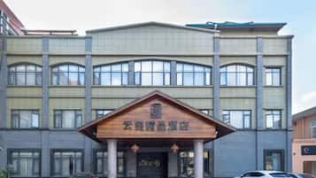 Un hotel de varios pisos con una entrada destacada que cuenta con un dosel de madera y señalización.