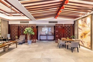 Un vestíbulo espacioso con mostrador de recepción, zona de estar y elementos decorativos como plantas y obras de arte.