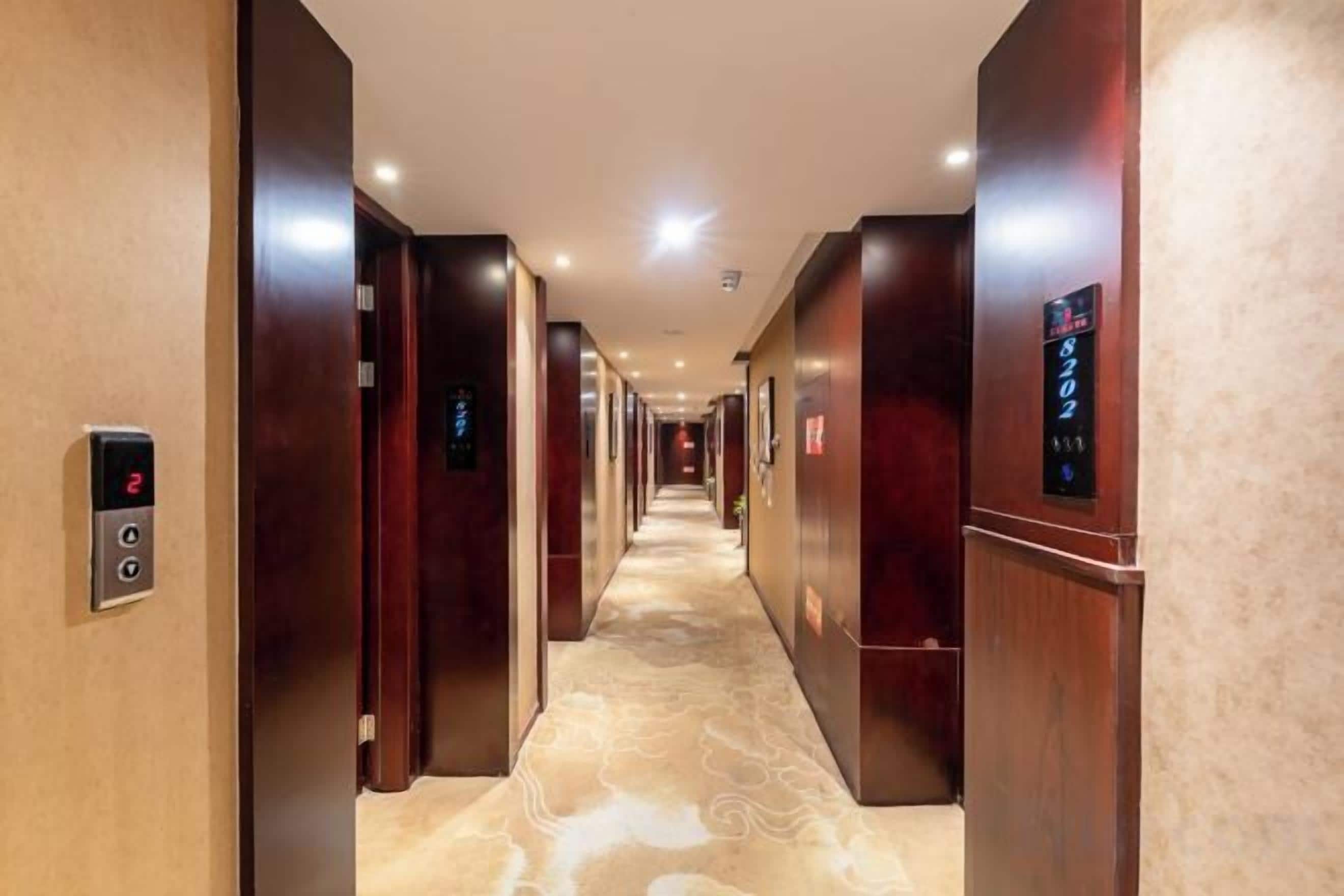 A hotel corridor with multiple elevators and a patterned carpet.