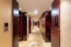 Pasillo de hotel con varios ascensores y alfombra estampada.