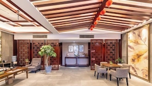 A traditional-style interior with wooden beams, a reception desk, and seating arrangements.