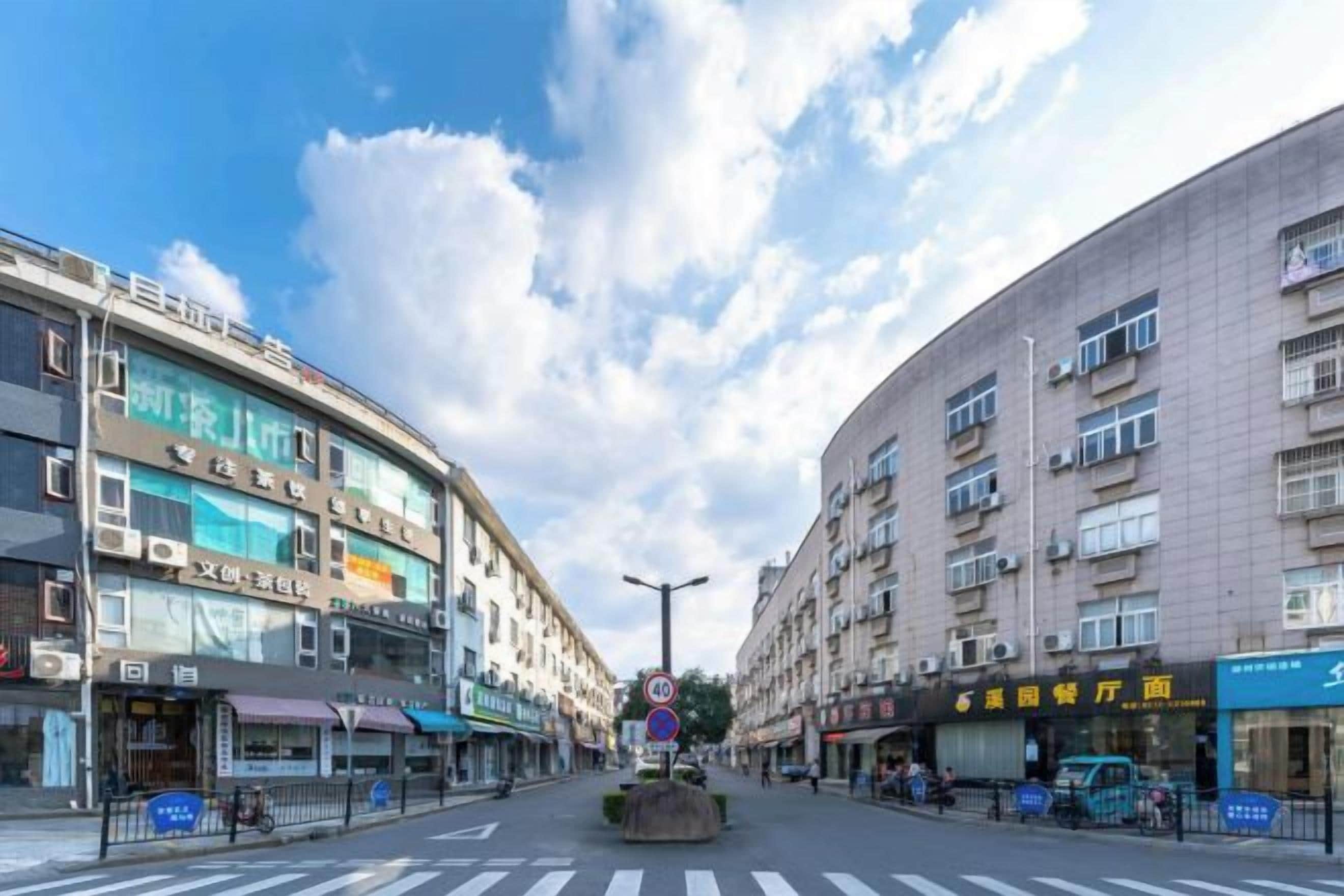 Vista de una calle con edificios de varios pisos, un paso de peatones y cielo despejado.