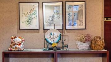 A reception desk with framed artwork, a decorative globe, and a small statue.