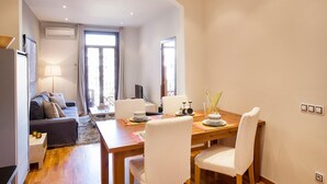Een moderne woonkamer met een bank, een eettafel met stoelen, een lamp en een televisie.