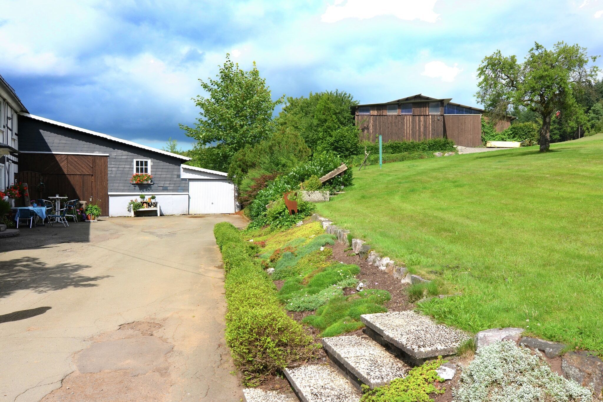 A residential property with a covered patio, a lawn, and a wooden barn.