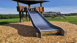 Un parque infantil con un tobogán y una estructura de madera.