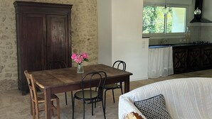 Un comedor con mesa y sillas de madera, un jarrón de flores y una pared de piedra.