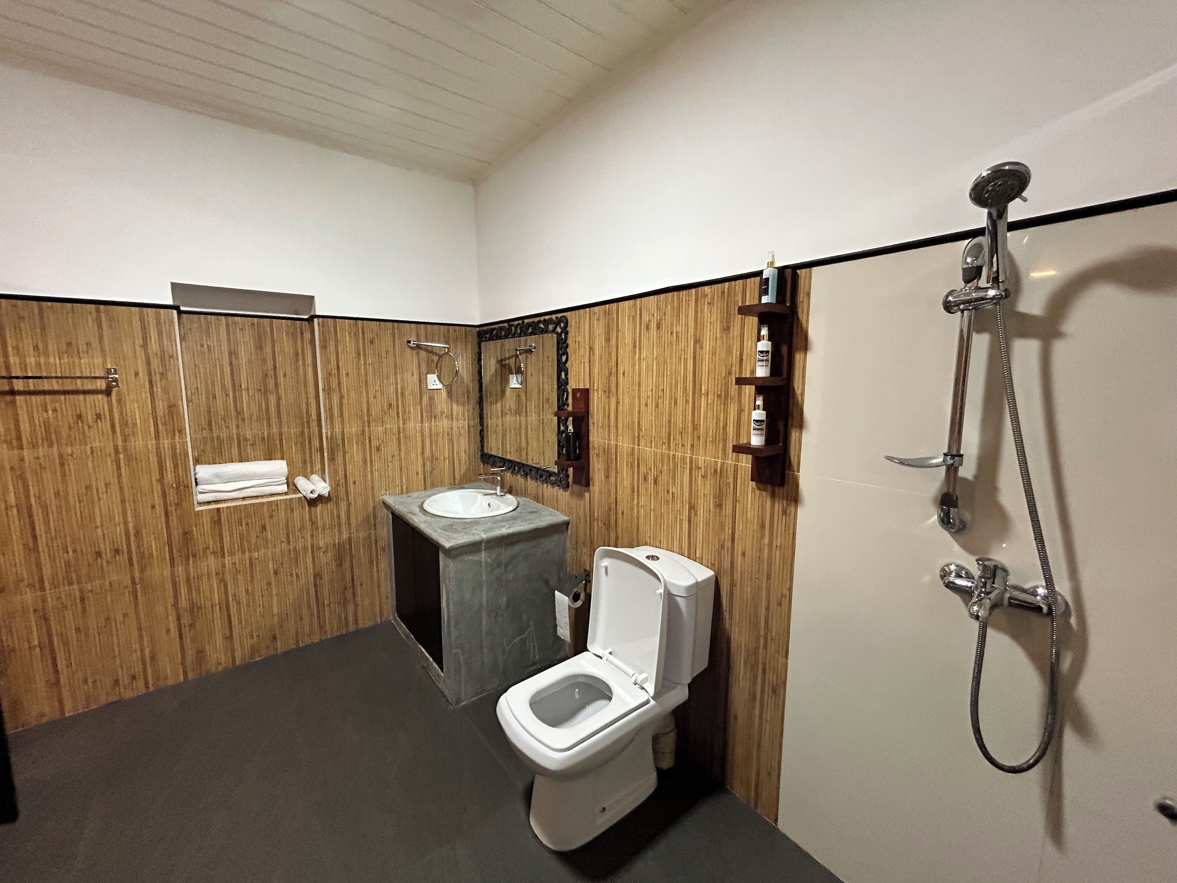 Moderni kylpyhuone, jossa on puinen seinäpaneeli, pesuallas, wc ja suihku.