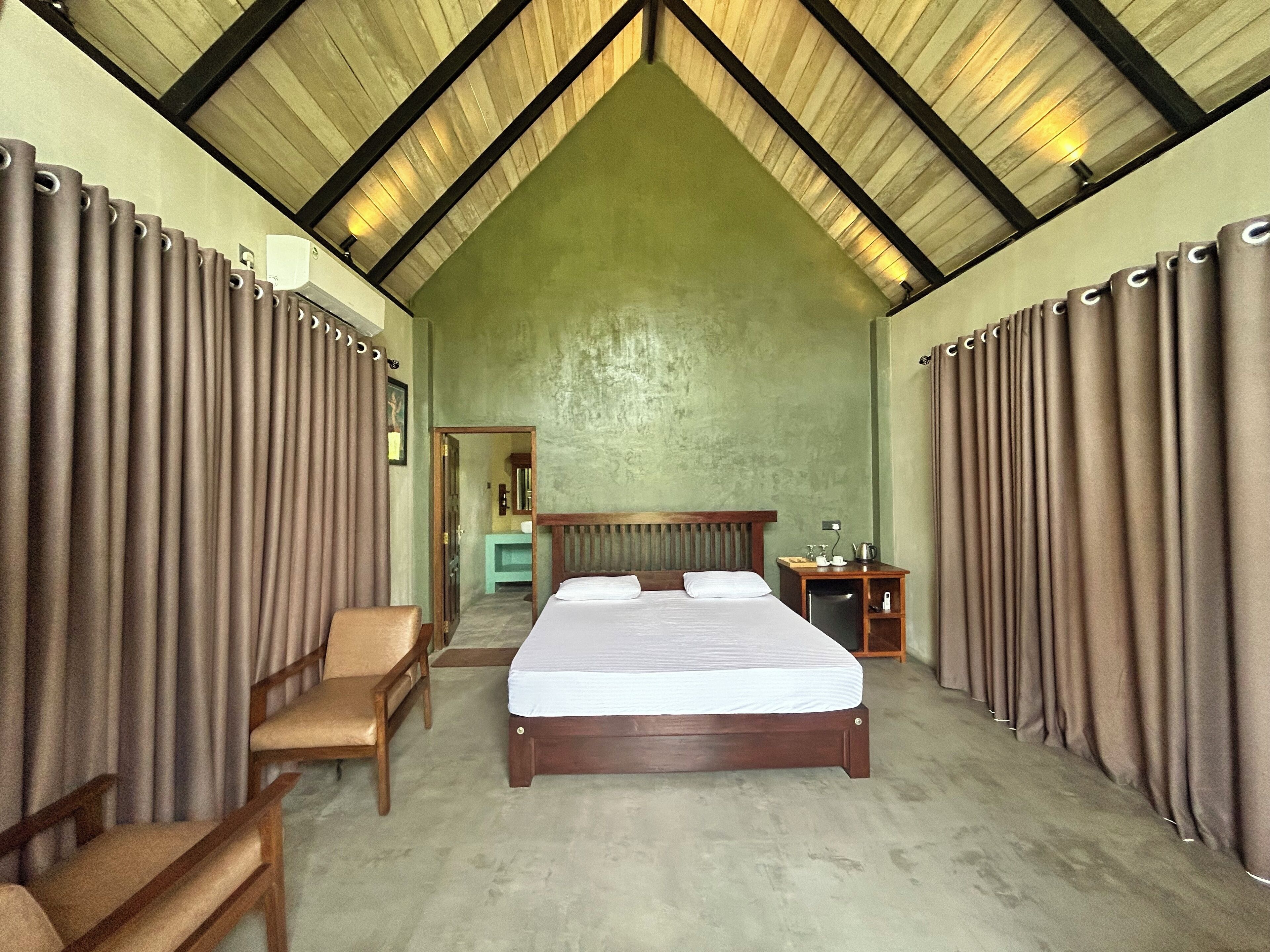 A spacious room with a large bed, wooden headboard, and a desk with a chair.