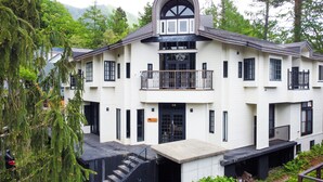 A white building with a black balcony and a large arched window. - Hakuba Mountain Lodge (Hakuba)