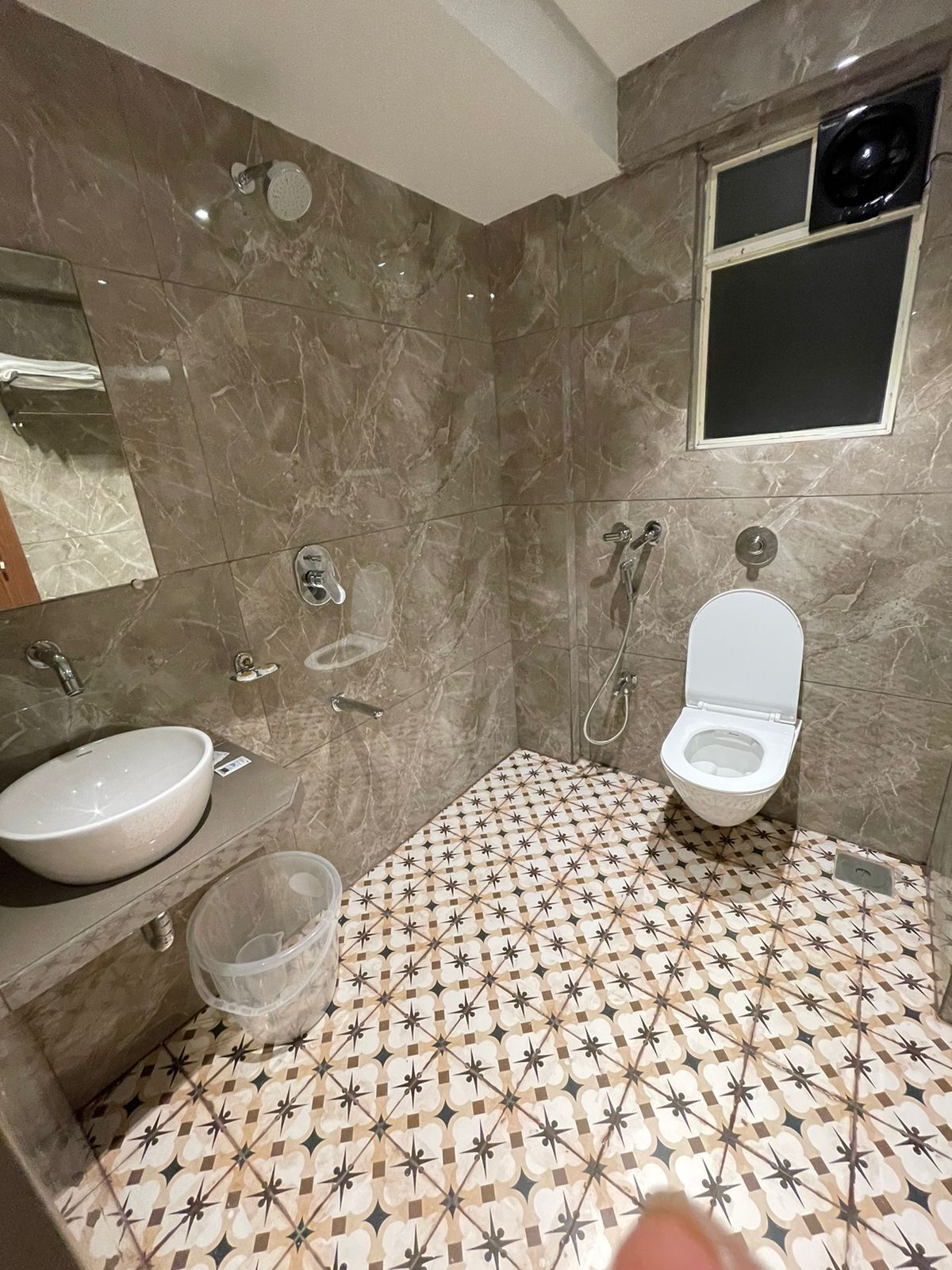 Un baño con pared de mármol, lavamanos, inodoro y ducha.