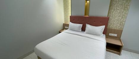 Una cama cuidadosamente tendida en una habitación de hotel con diseño moderno, que incluye un cabecero con detalles verticales dorados y un papel pintado con diseño en la pared contigua.