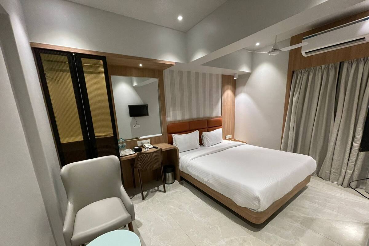 Hotelkamer met een bed, een bureau, een stoel, een klein tafeltje, een spiegel en een airconditioning.