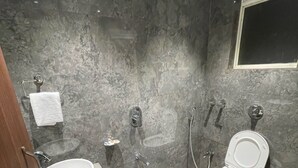 A modern bathroom with a sink, toilet, and shower. - Hotel The West Coast (Vasai)
