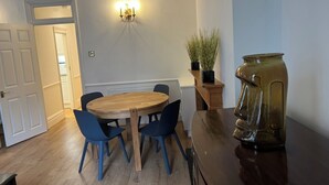 Un'area pranzo con un tavolo rotondo in legno e sedie blu, una pianta in vaso e un vaso decorativo su un bancone in legno.