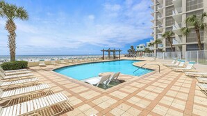 Ein Poolbereich mit Liegestühlen, einer Palme und Blick aufs Meer.
