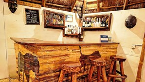 A rustic bar area with wooden stools and a bar counter. - Pumba Safari Cottages (Kichwamba)
