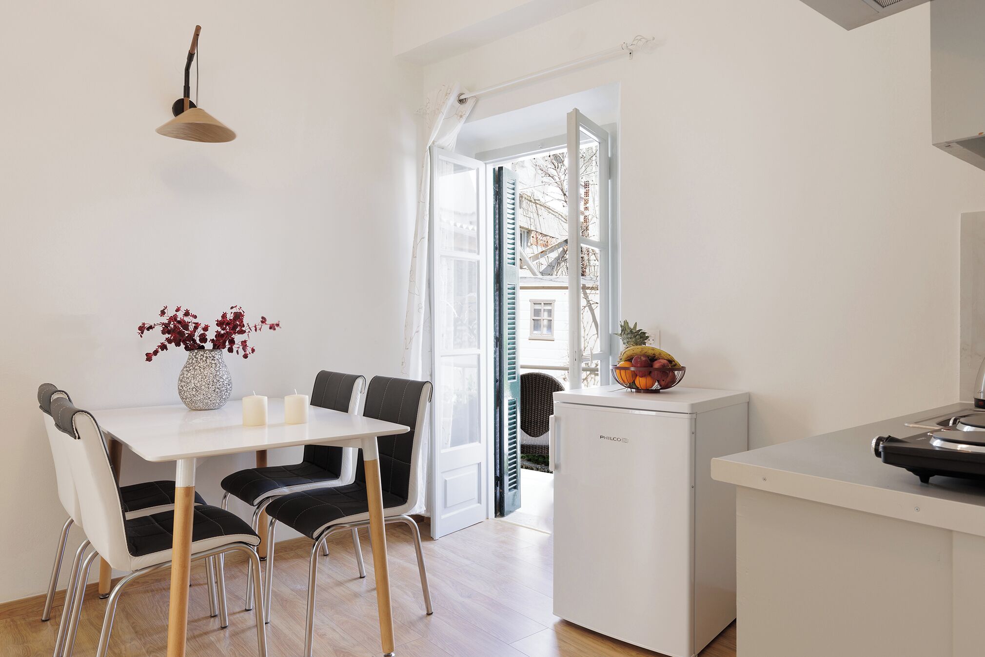 Een moderne keuken met een eettafel, stoelen, een koelkast en uitzicht door een open deur.