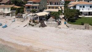 A coastal property with a beach, a covered outdoor seating area, and a staircase leading to a building.