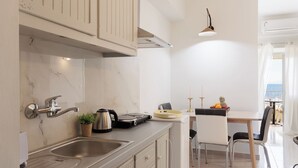 A modern kitchen with a marble countertop, stainless steel sink, and a dining area with a table and chairs.