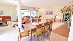 A spacious living area with a dining table, chairs, sofas, and a large window.