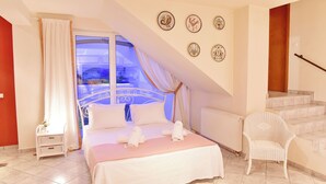 A bedroom with a bed, a chair, a window, and a staircase.