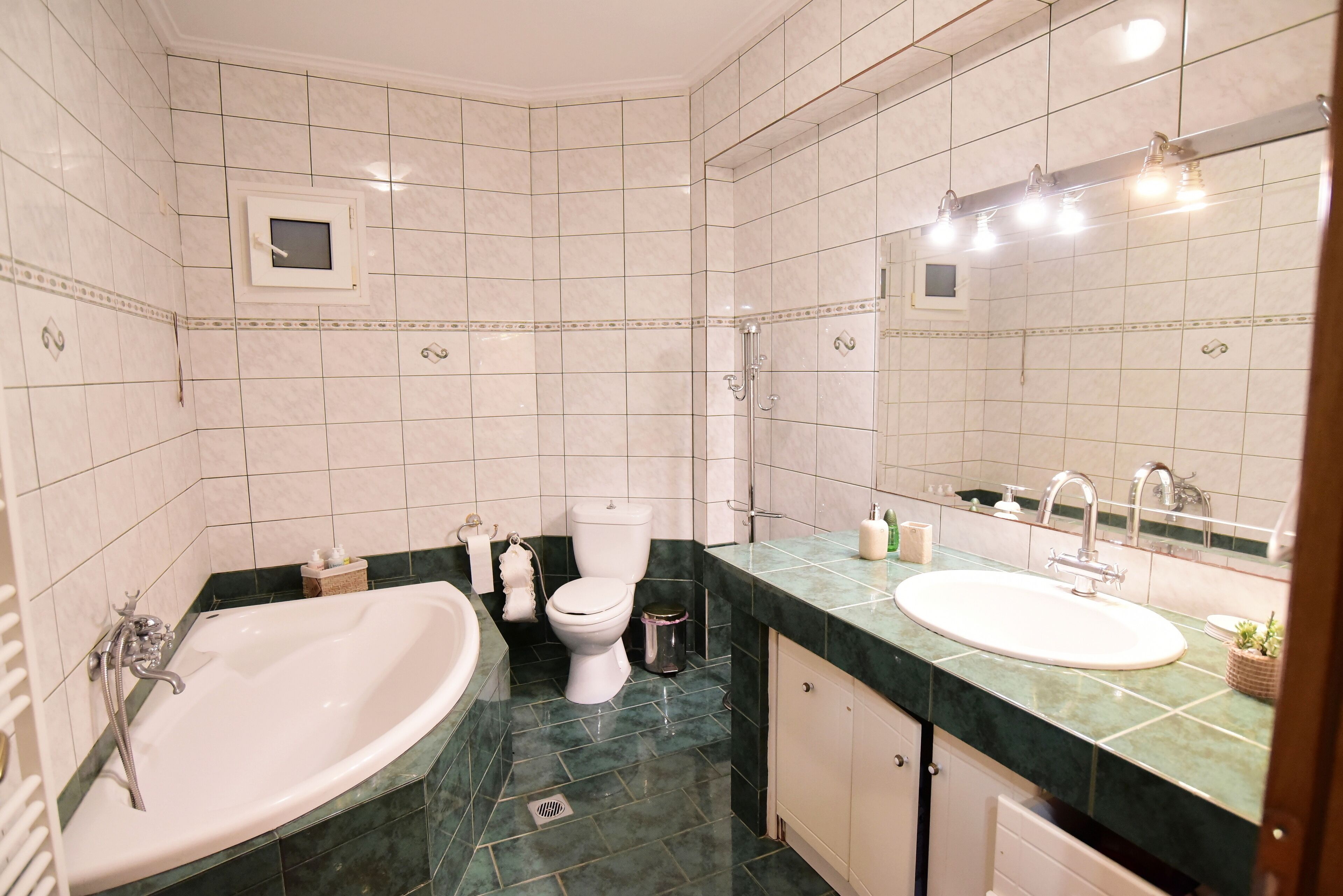 Une salle de bain avec une baignoire, des toilettes, un lavabo et un grand miroir.