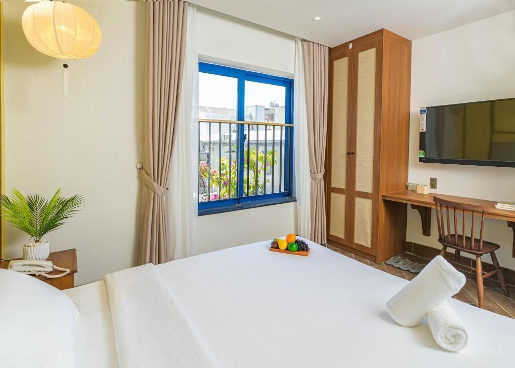 A hotel room with a bed, a desk, a television, and a window with curtains.