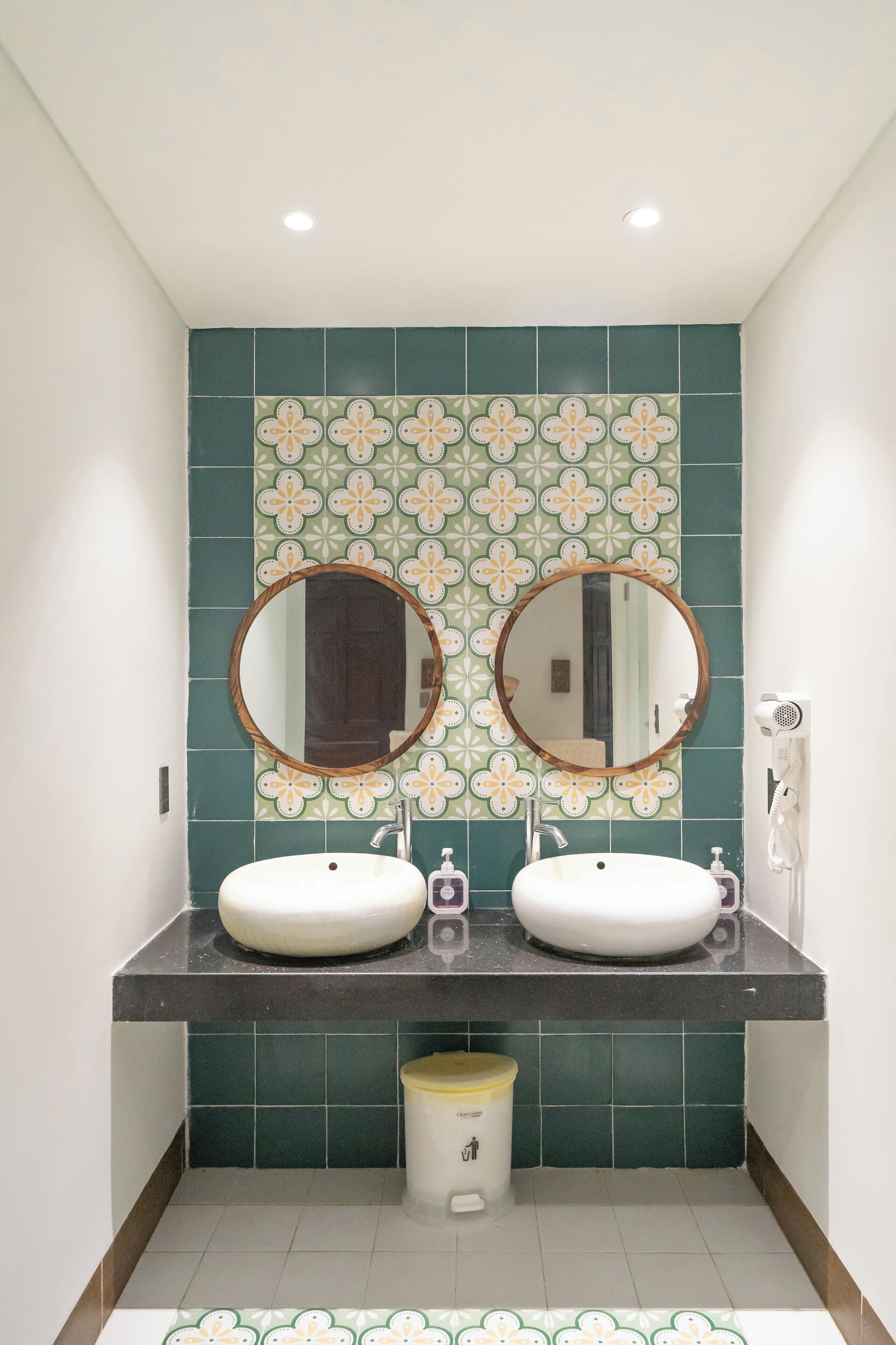 A bathroom with two sinks, a mirror, and a hairdryer.