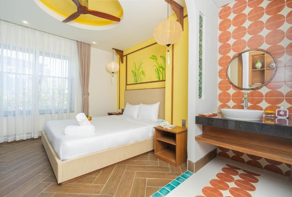 A hotel room with a bed, bedside table, lamp, and a bathroom with a sink and mirror.