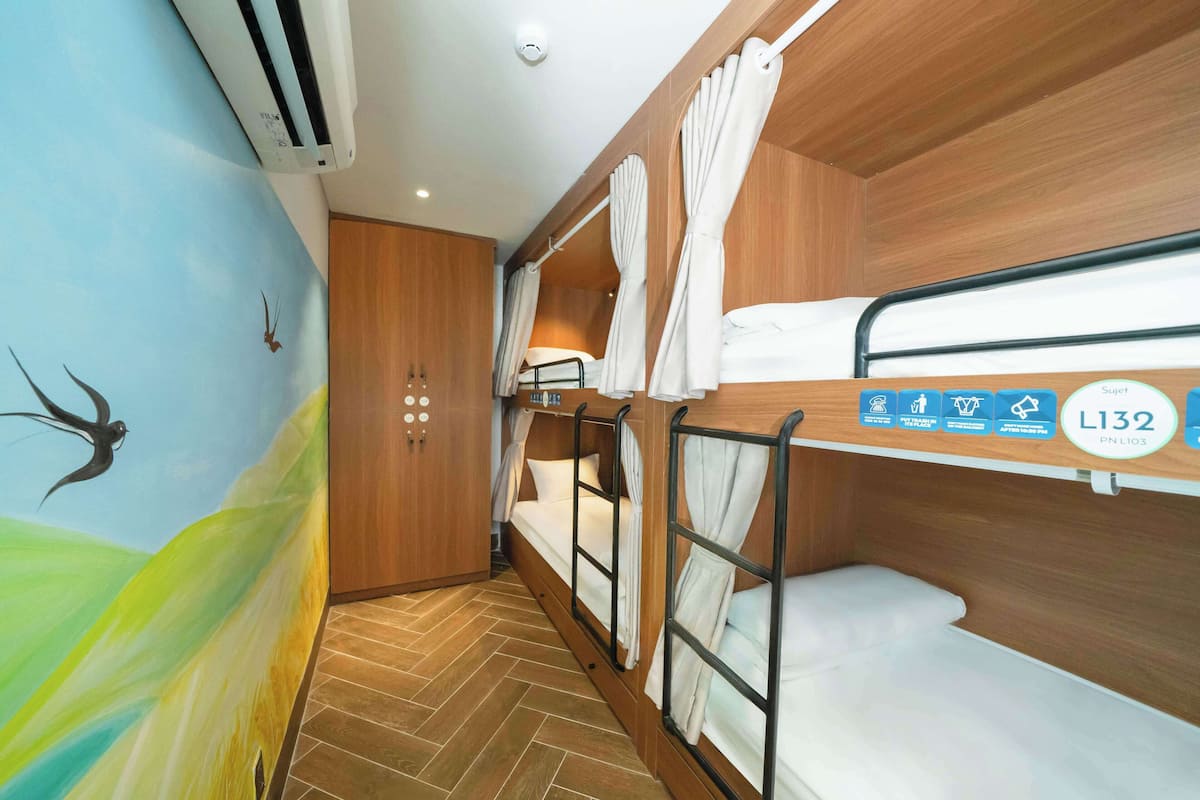 A bunk room with wooden walls, a mural, and a ceiling fan.