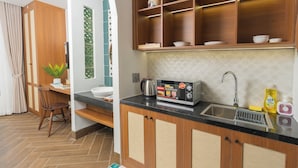 A kitchen with wooden cabinets, a black countertop, a sink, and a microwave. - Sujet Hotel Da Nang (Da Nang)