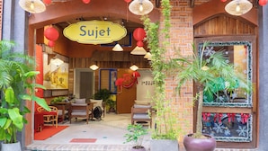 A cozy interior with a brick wall, a wooden archway, and a sign reading "Sujet." There are potted plants, a seating area with chairs, and a small pool. - Sujet Hotel Da Nang (Da Nang)