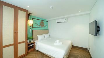Une chambre d’hôtel équipée d’un lit, d’une télévision, d’un climatiseur et d’une armoire en bois.