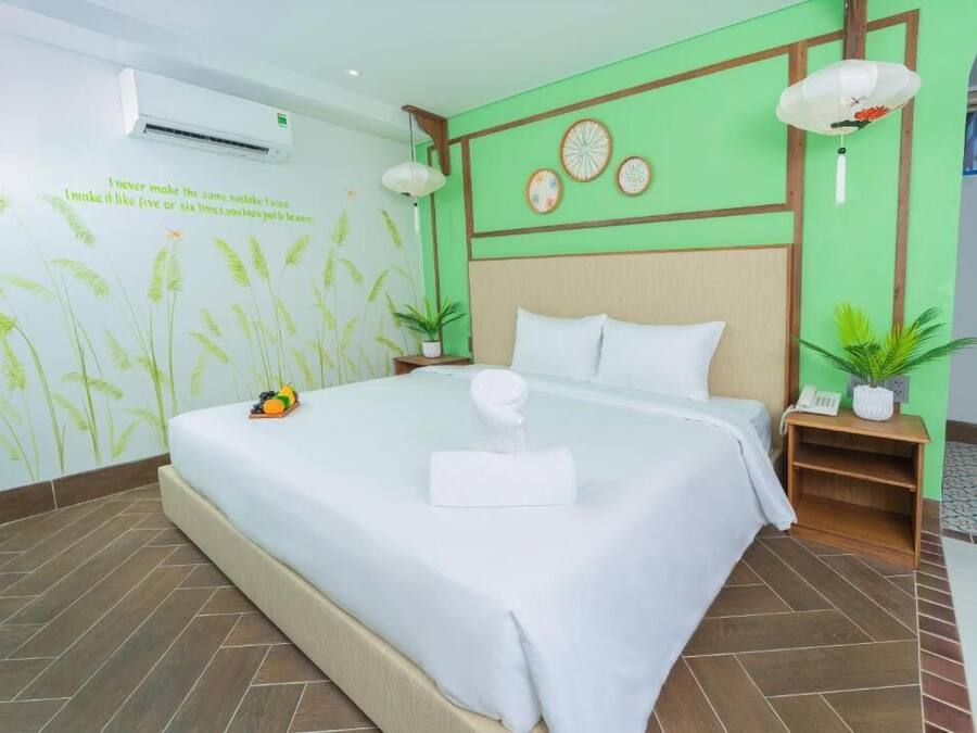 Una cama bien hecha con sábanas blancas y una toalla, un aire acondicionado de pared y una decoración mural.