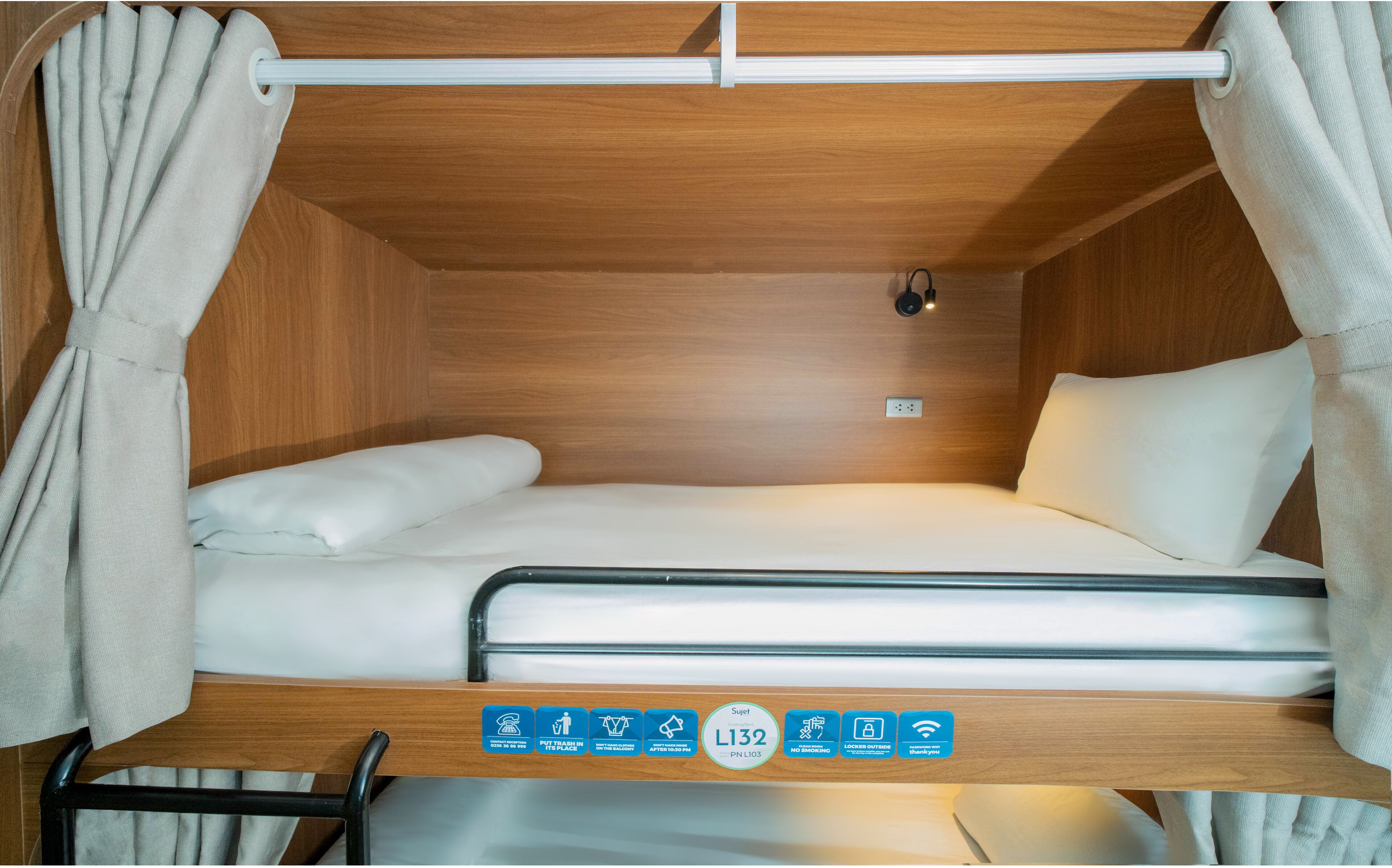 A compact, well-lit sleeping area with a single bed, a small table, and a curtain.