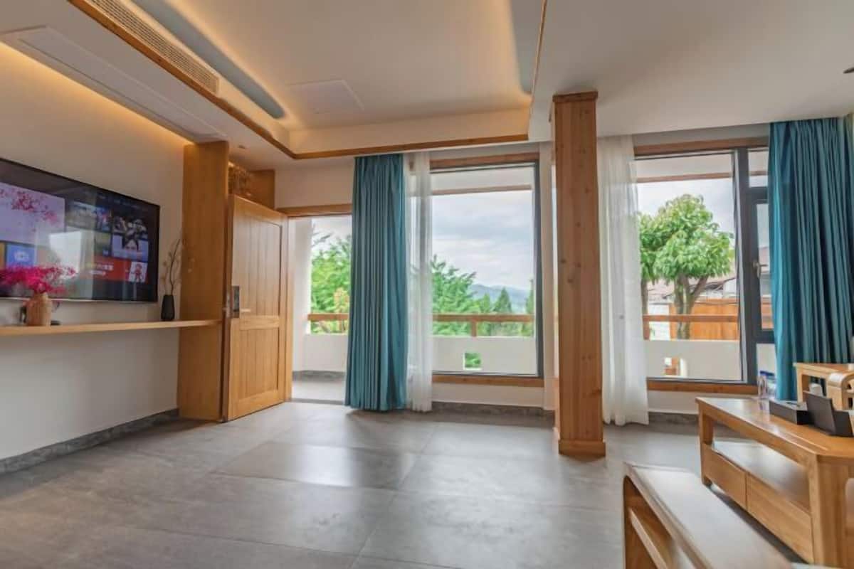 Une pièce spacieuse avec une grande fenêtre, un bureau en bois et un téléviseur fixé au mur.